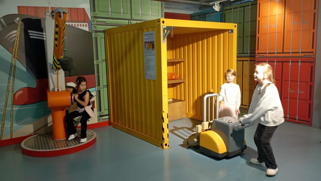 Przy atrapie terminalu kontenerowego pracują 3 uczennice klasy 1c, jedna operuje dźwigiem.