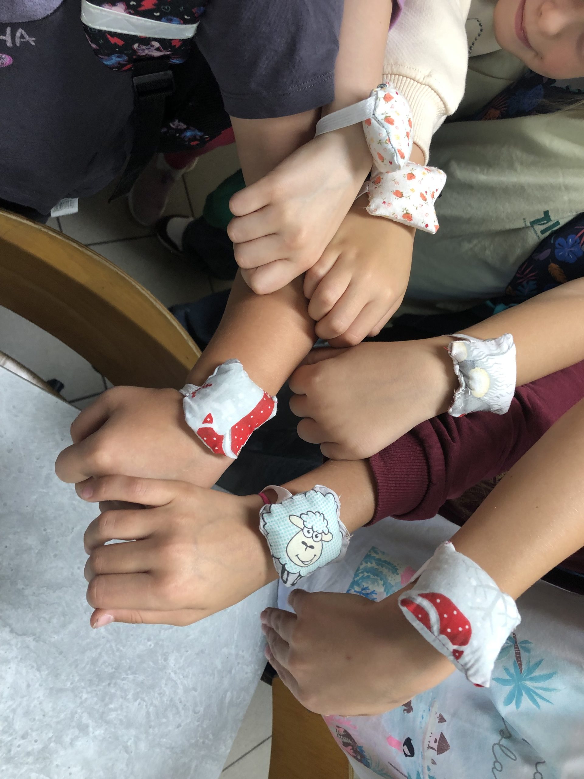 sześć rąk prezentuje na nadgarstkach poduszeczki do igieł