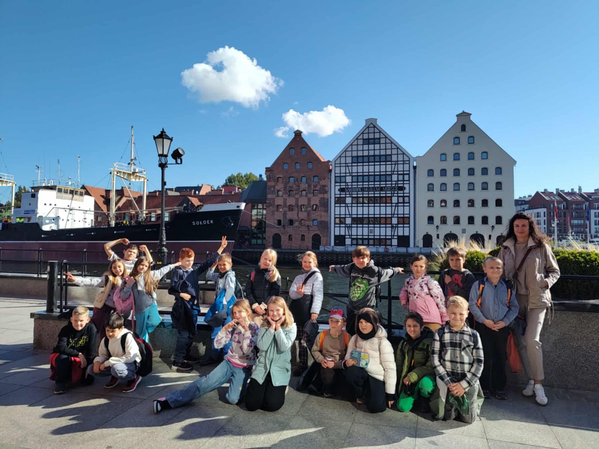  Grupa uczniów klasy 3c pozuje do zdjęcia przed Narodowym Muzeum Morskim w Gdańsku, w tle statek Sołdek i zabytkowe kamienice nad Motławą.