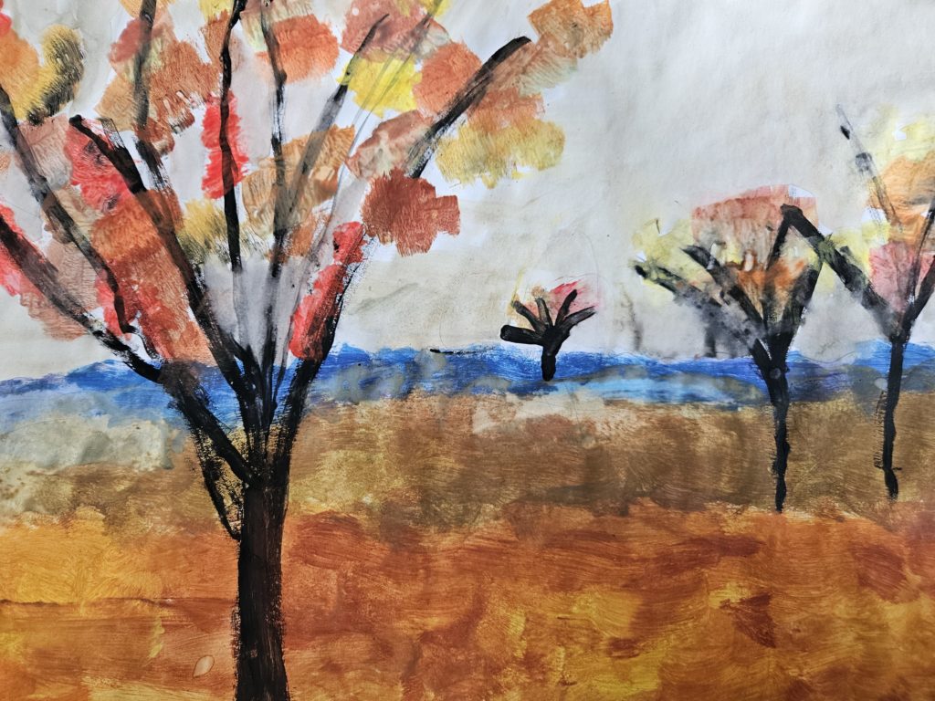 Praca przedstawia jesienny krajobraz z polami i pojedynczymi drzewami. Całość w barwach jesiennych