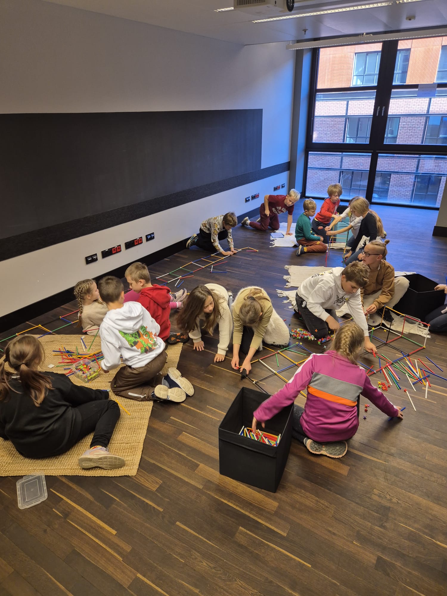 W dużej sali edukacyjne jest 12 dzieci. Dzieci są podzielone na grupy i budują z klocków mosty