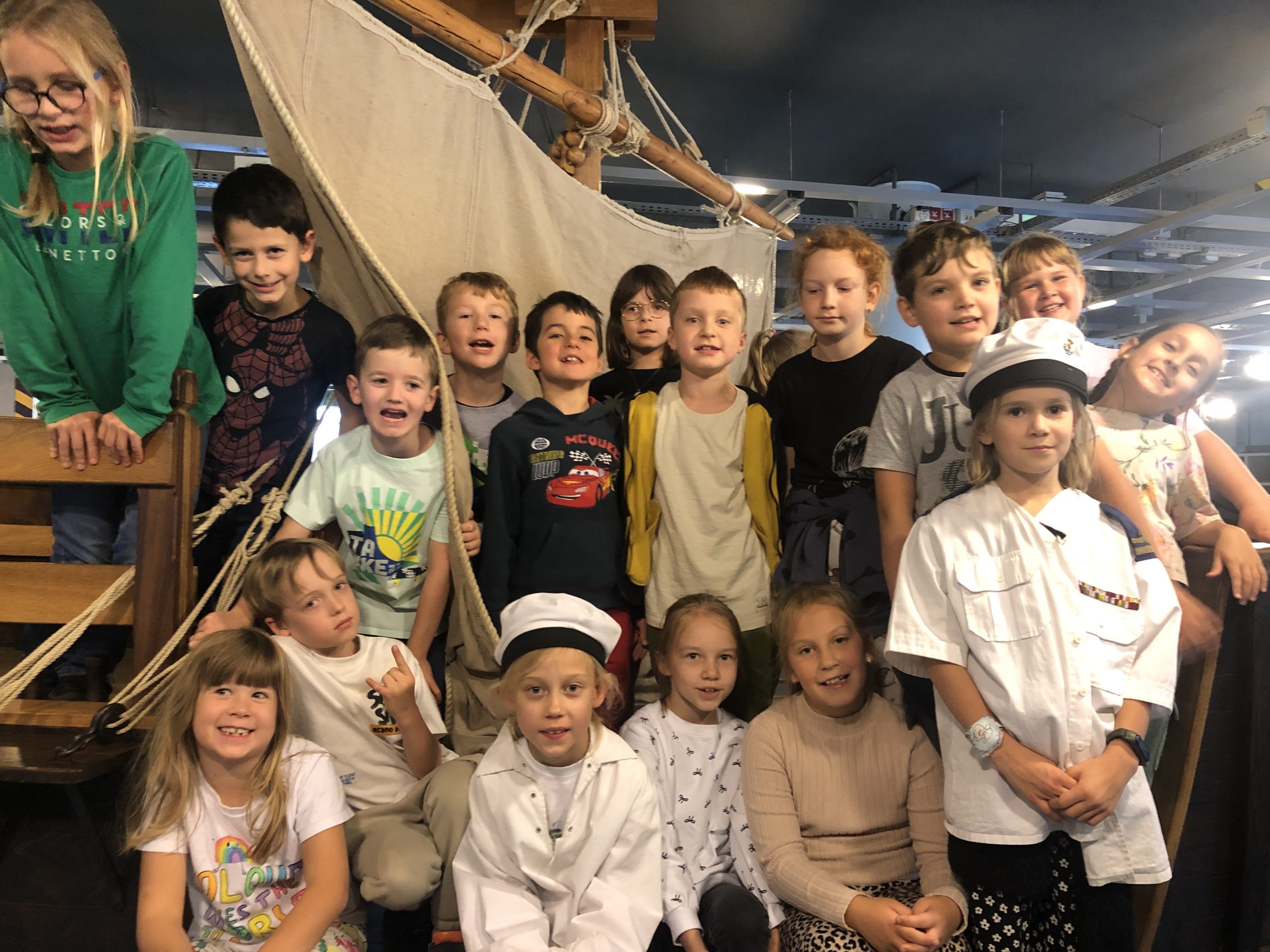 16 uczniów stoi na makiecie statku.