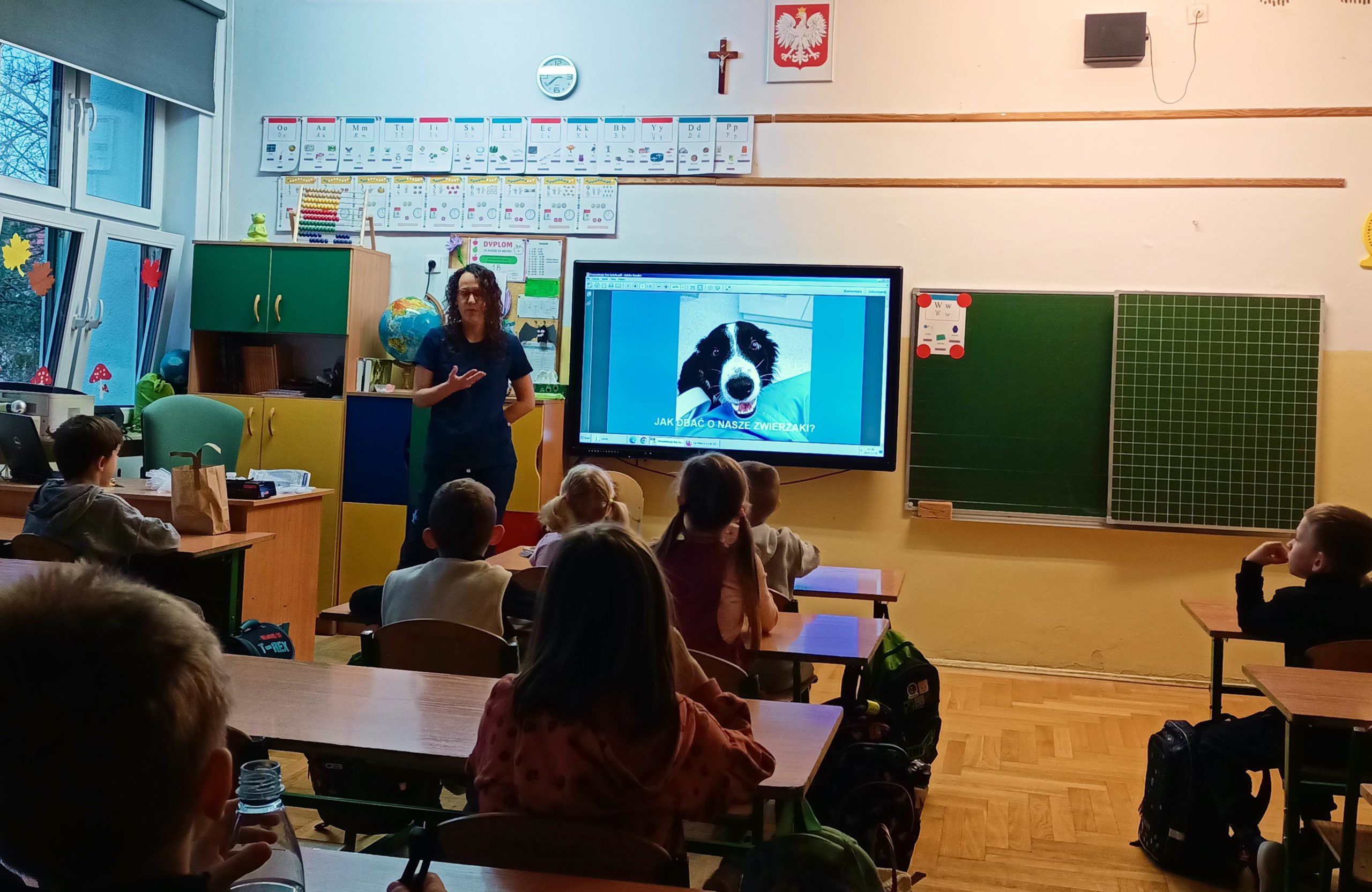 377 Pani weterynarz opowiada dzieciom siedzącym w ławkach o swojej pracy. Na ekranie wyświetla się prezentacja o zwierzętach.