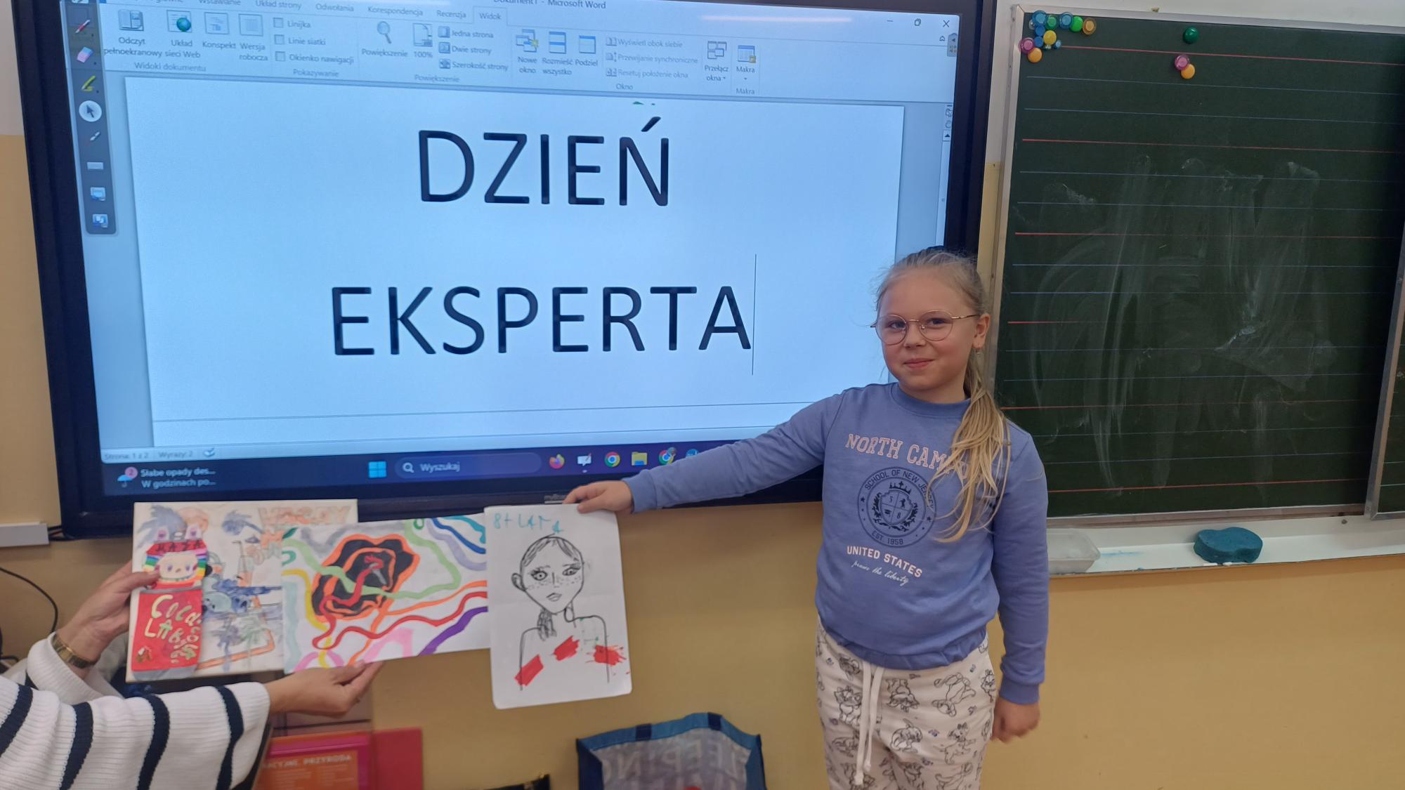 dziewczynka prezentuje swoje prace plastyczne 