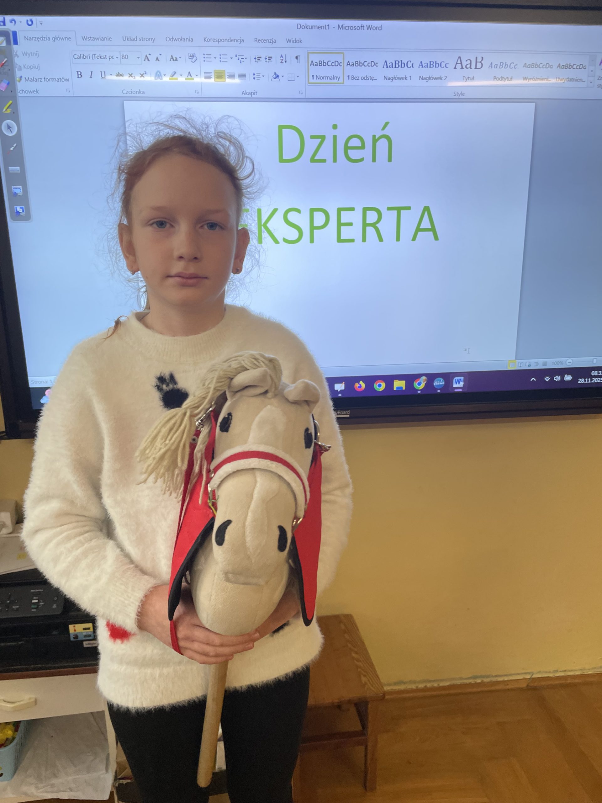 Dziewczynka stoi w rękach trzyma głowę konia na kiju.