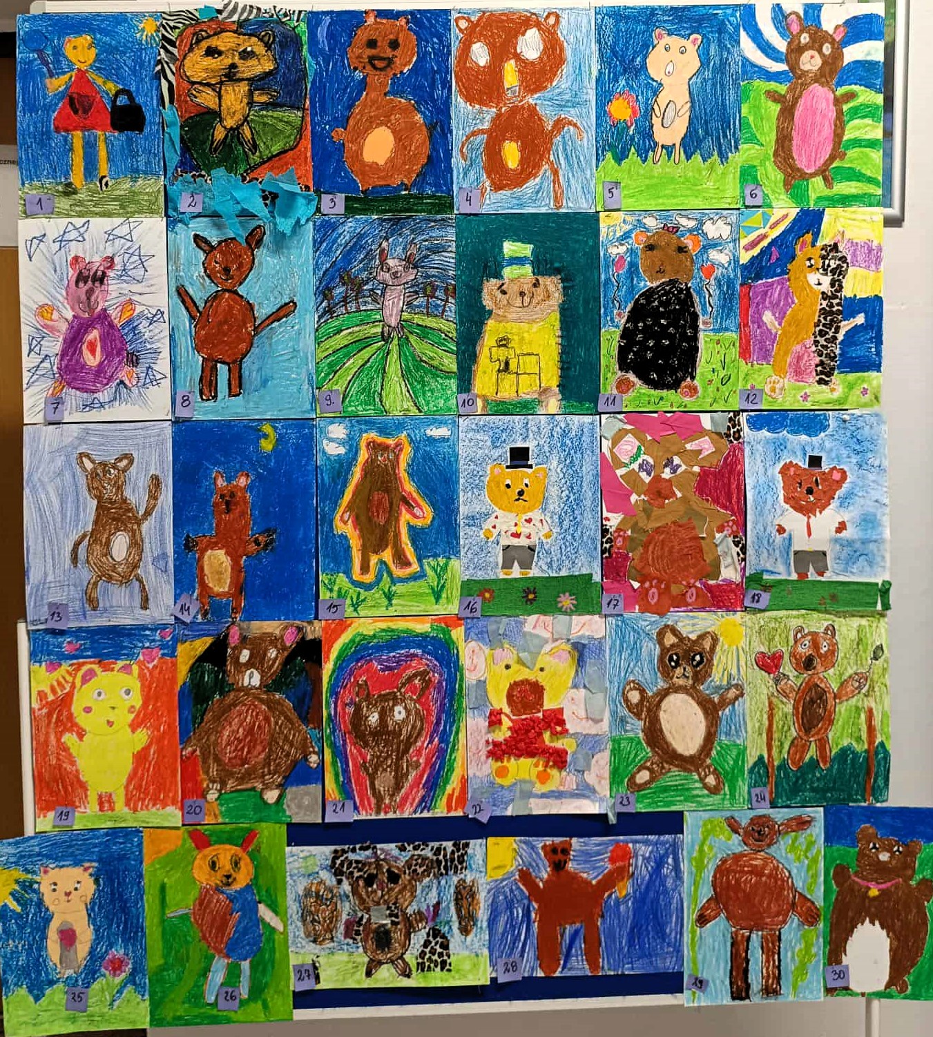 Zdjęcie przedstawia tablicę ekspozycyjną z kolorowymi pracami plastycznymi dzieci, uczestników konkursu „Świetlicowy Konkurs Plastyczny – Miś”. Na ciemnoniebieskim tle przypiętych jest kilkanaście rysunków misiów wykonanych różnymi technikami.