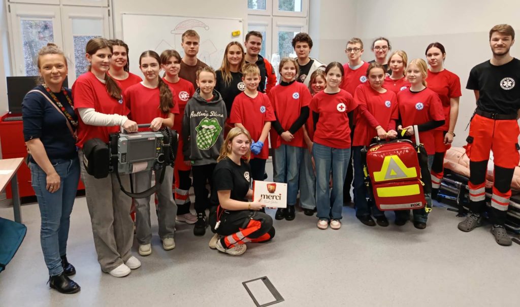 Na środku sali do ćwiczeń Zakładu Ratownictwa Medycznego GUMed ponad dwudziestoosobowa grupa studentów ratownictwa GUMed oraz uczniów Koła PP HOPR wraz z nauczycielką.