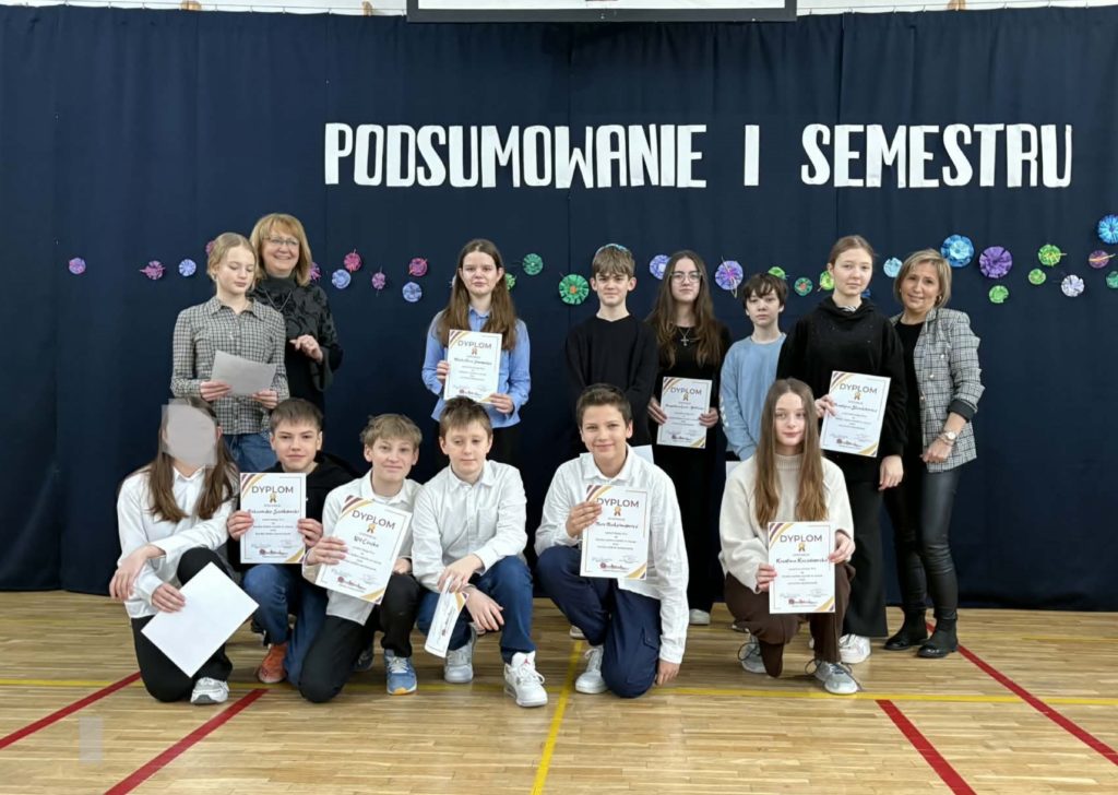 Na sali gimnastycznej stoi grupa wyróżnionych uczniów wraz z dyrekcją, wychowawcami oraz nauczycielami przedmiotowymi, za wysokie osiągnięcia w nauce i bardzo dobre lub wzorowe zachowanie