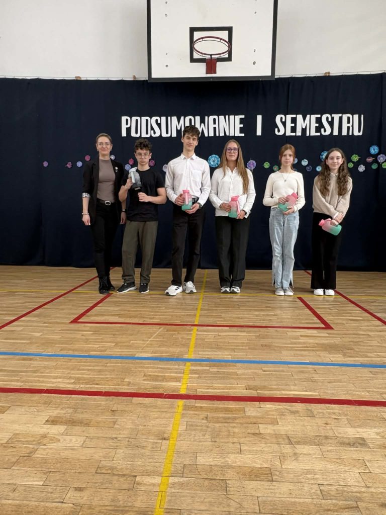 Wyróżnieni uczniowie za konkursy sportowe trzymają dyplomy i nagrody rzeczowe