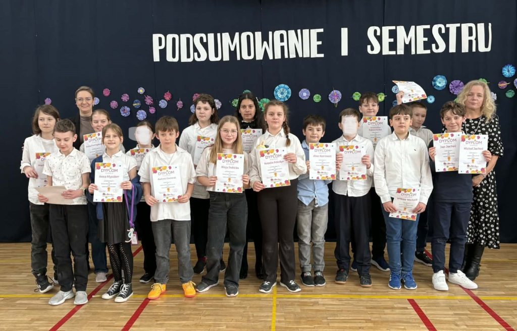 Na sali gimnastycznej stoi grupa wyróżnionych uczniów wraz z dyrekcją, wychowawcami oraz nauczycielami przedmiotowymi, za wysokie osiągnięcia w nauce i bardzo dobre lub wzorowe zachowanie