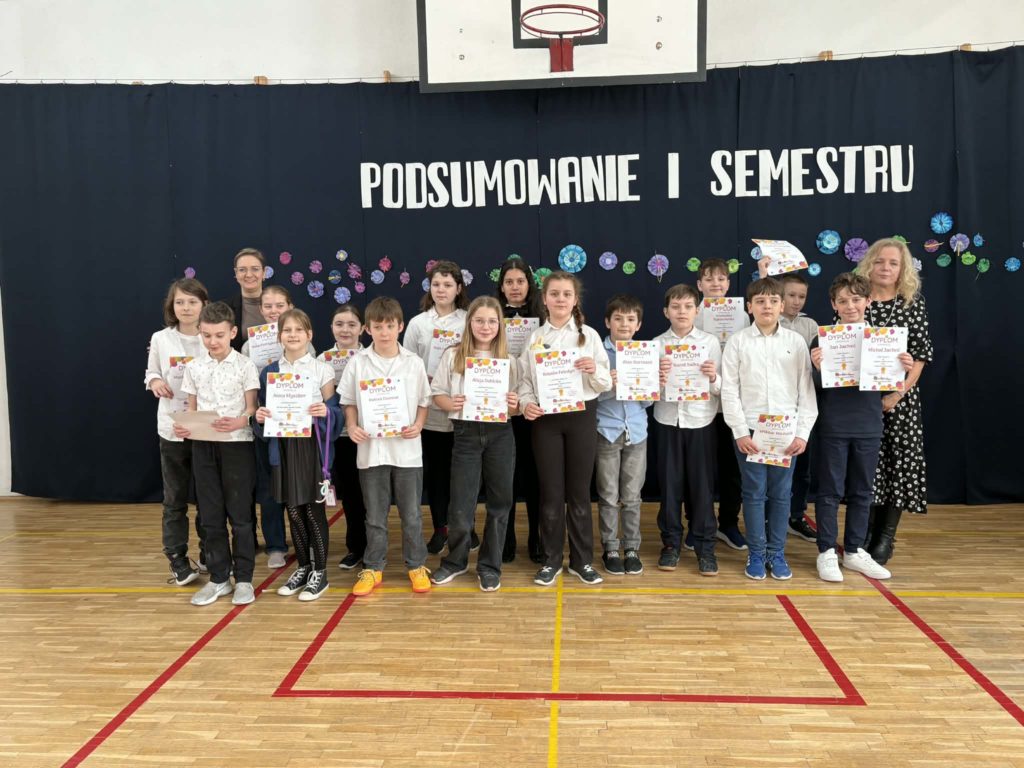 Na sali gimnastycznej stoi grupa wyróżnionych uczniów wraz z dyrekcją, wychowawcami oraz nauczycielami przedmiotowymi, za wysokie osiągnięcia w nauce i bardzo dobre lub wzorowe zachowanie