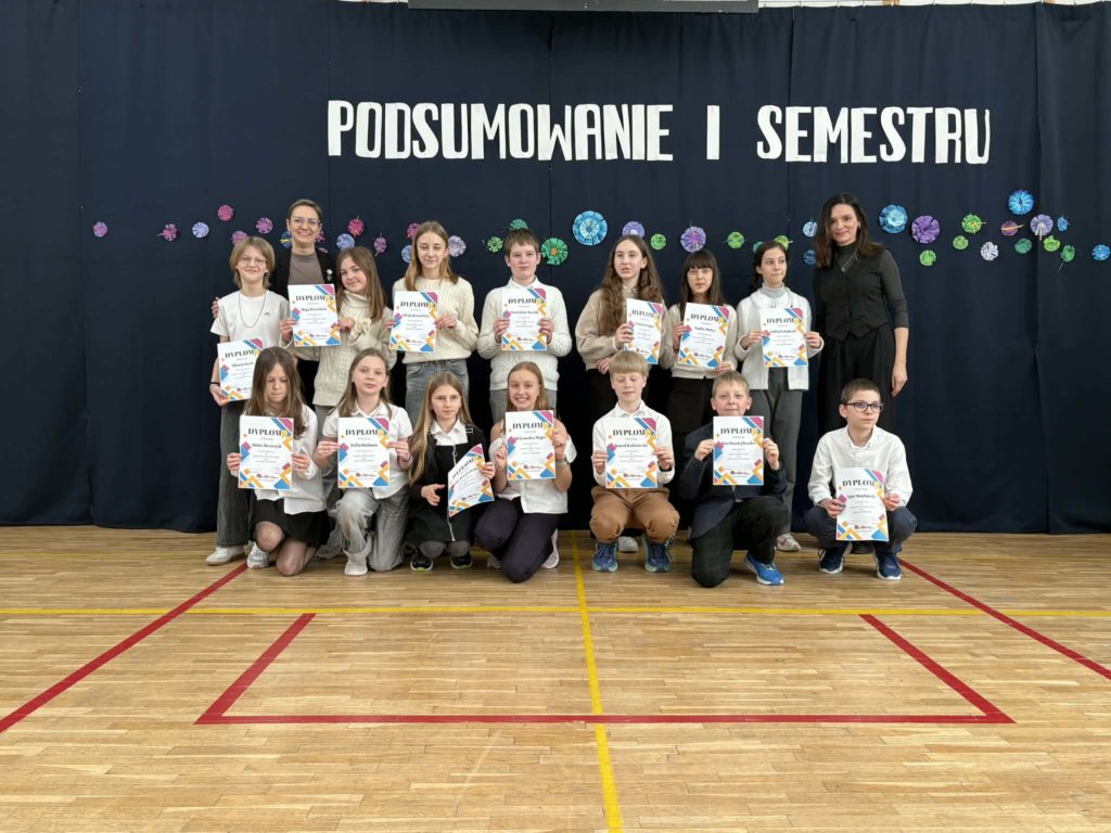 Na sali gimnastycznej stoi grupa wyróżnionych uczniów wraz z dyrekcją, wychowawcami oraz nauczycielami przedmiotowymi, za wysokie osiągnięcia w nauce i bardzo dobre lub wzorowe zachowanie