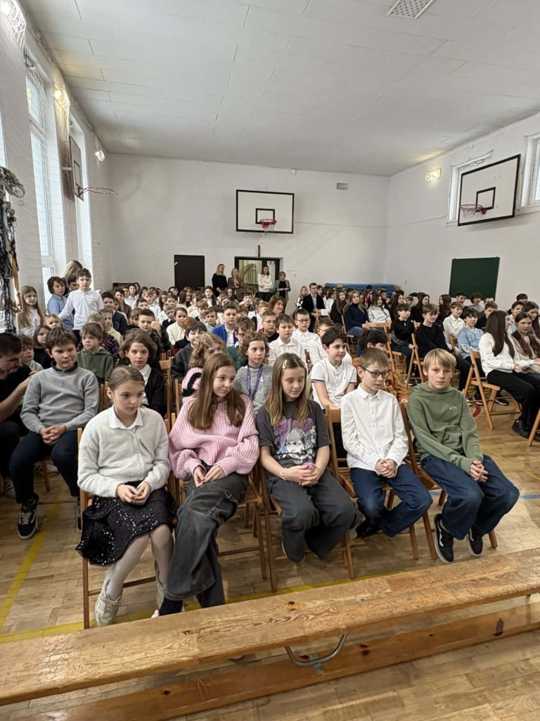 Duża grupa uczniów siedzi na sali gimnastycznej na apelu podsumowującym I semestr nauki 