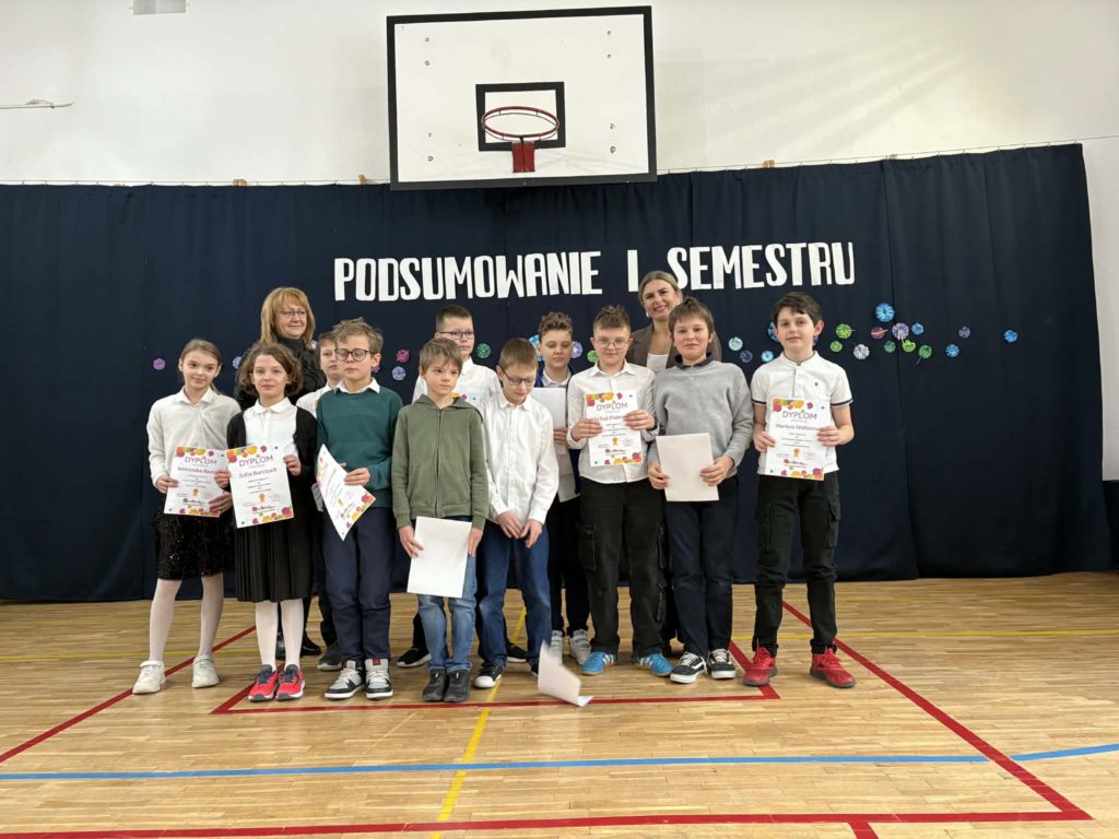 Na sali gimnastycznej stoi grupa wyróżnionych uczniów wraz z dyrekcją, wychowawcami oraz nauczycielami przedmiotowymi, za wysokie osiągnięcia w nauce i bardzo dobre lub wzorowe zachowanie