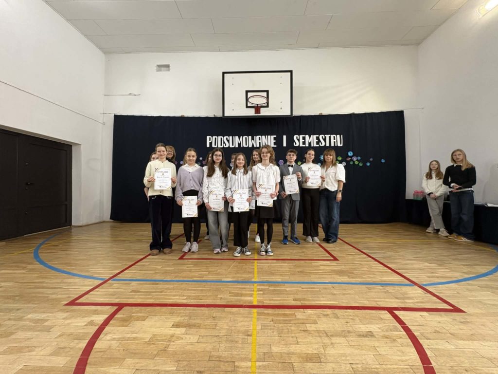 Na sali gimnastycznej stoi grupa wyróżnionych uczniów wraz z dyrekcją, wychowawcami oraz nauczycielami przedmiotowymi, za wysokie osiągnięcia w nauce i bardzo dobre lub wzorowe zachowanie