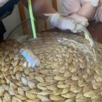 wie osoby w rękawiczkach tworzą przezroczystą „bańkę” nad ziarnami, używając słomki.