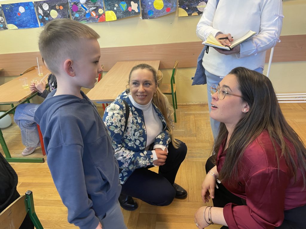 W klasie 8 letni chłopiec rozmawia z dwiema paniami które przy nim kucają