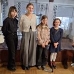 Sześć dziewczynek stoi obok siebie w eleganckim wnętrzu i pozuje do zdjęcia. Ubrane są w schludne ubrania. 