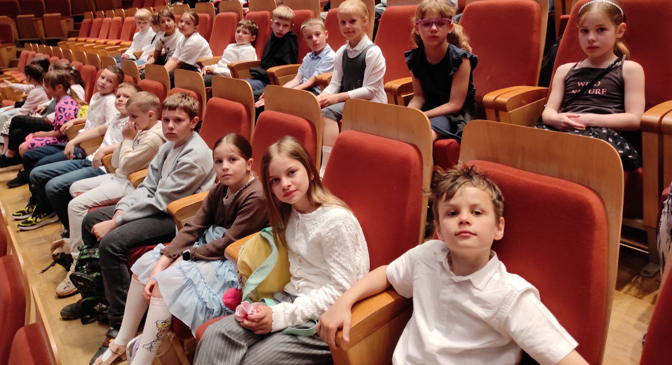 Przed fasadą ceglastego budynku z napisem: „Polska Filharmonia Bałtycka imienia Fryderyka Chopina” stoi grupa uczniów klasy 1c.