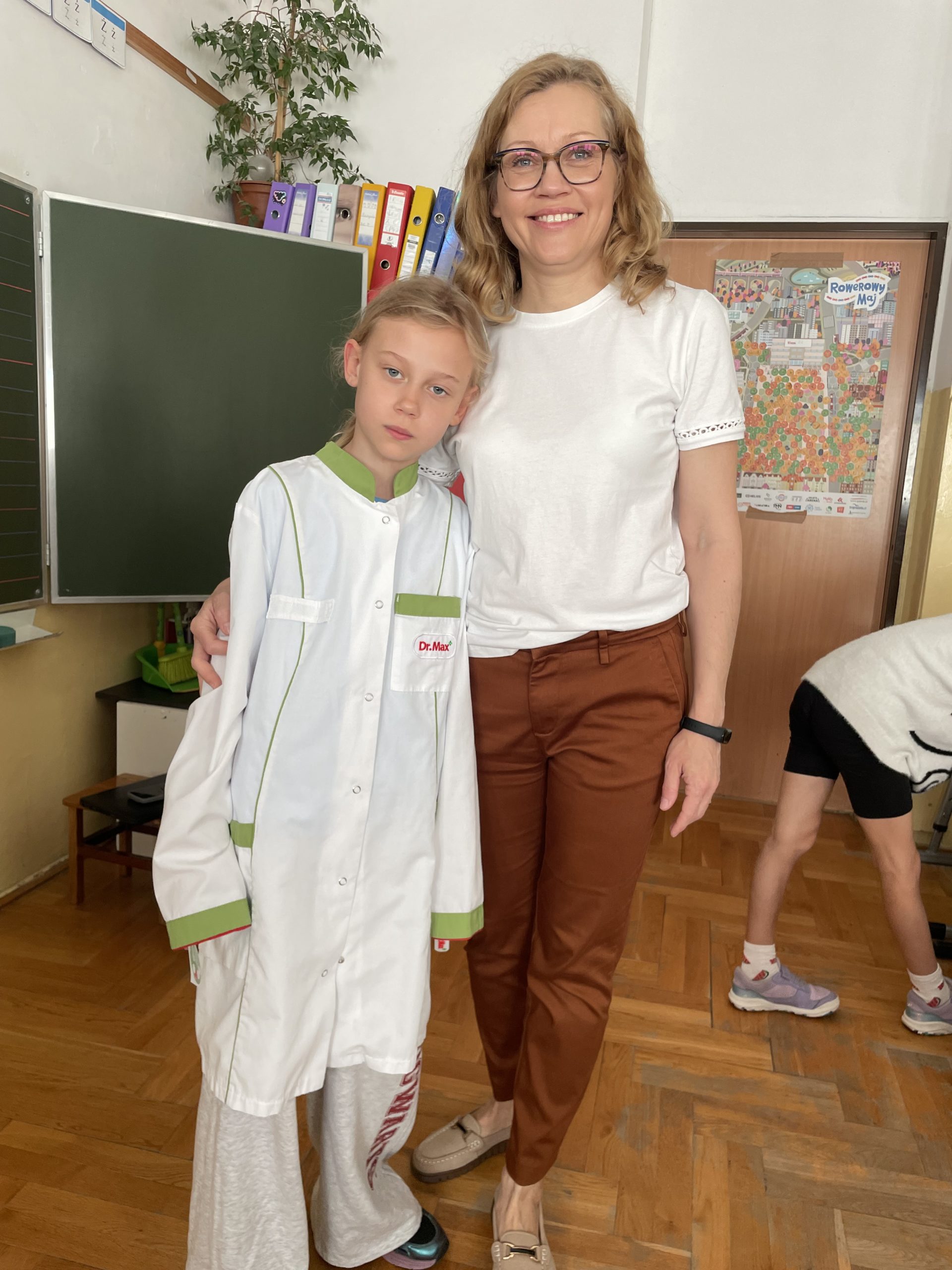 Stoi pani i uczennica ubrana w fartuch farmaceuty.