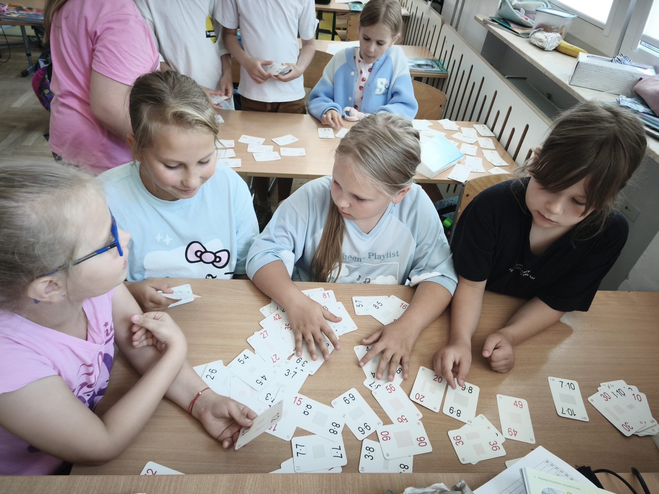 Cztery uczennice siedzą przy stole i grają w karty.