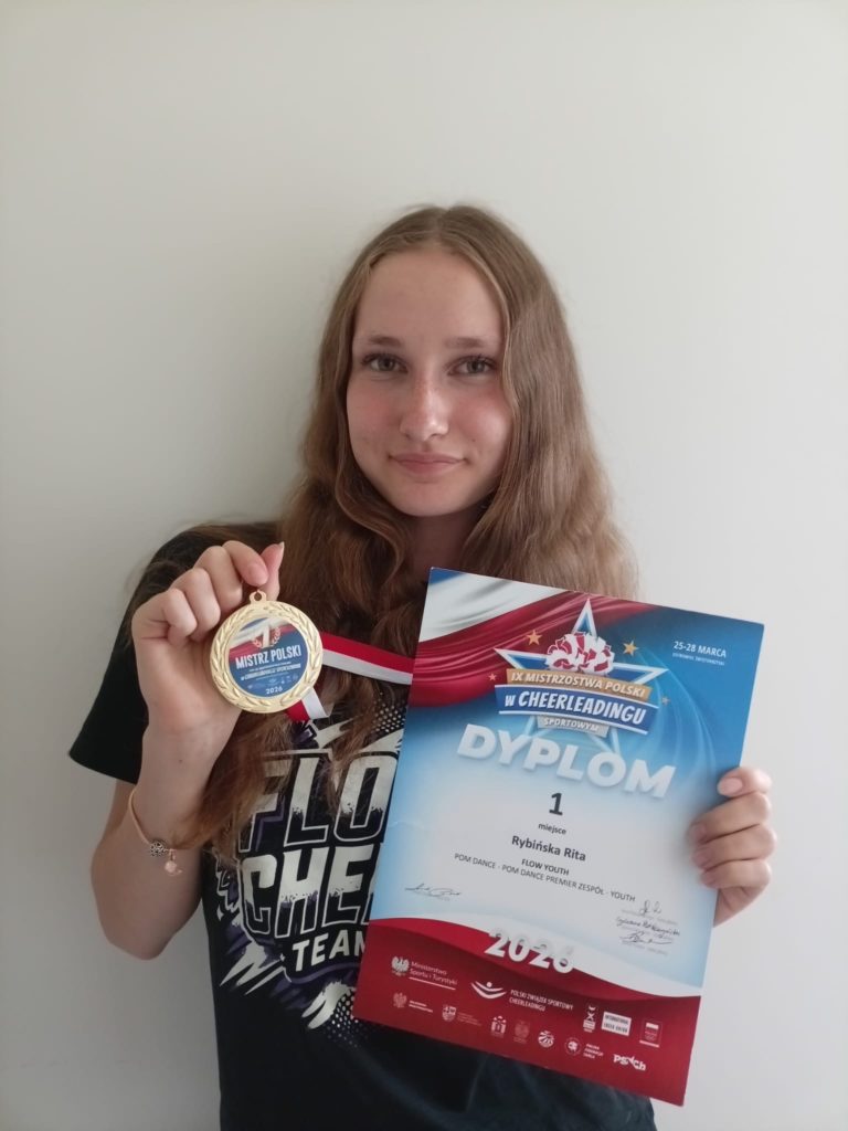 Uczennica prezentuje medal Mistrzyni Polski oraz dyplom za I miejsce w cheerleadingu sportowym.