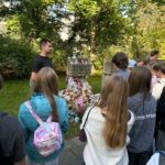 Grupa uczniów i nauczyciel historii stają przed Pomnikiem na cmentarzu na Zaspie